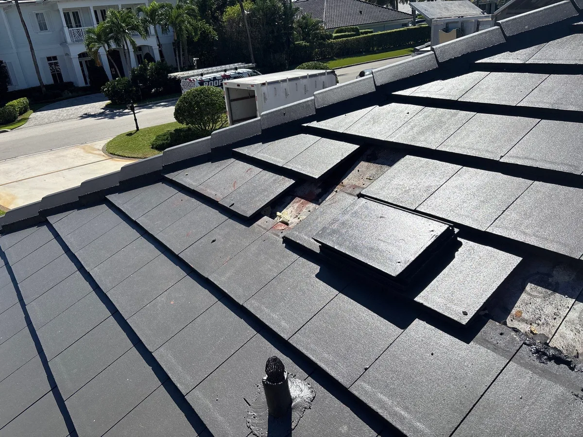Flat concrete tile lifted and stacked around a pipe penetration during a roof repair in Boca Raton, FL