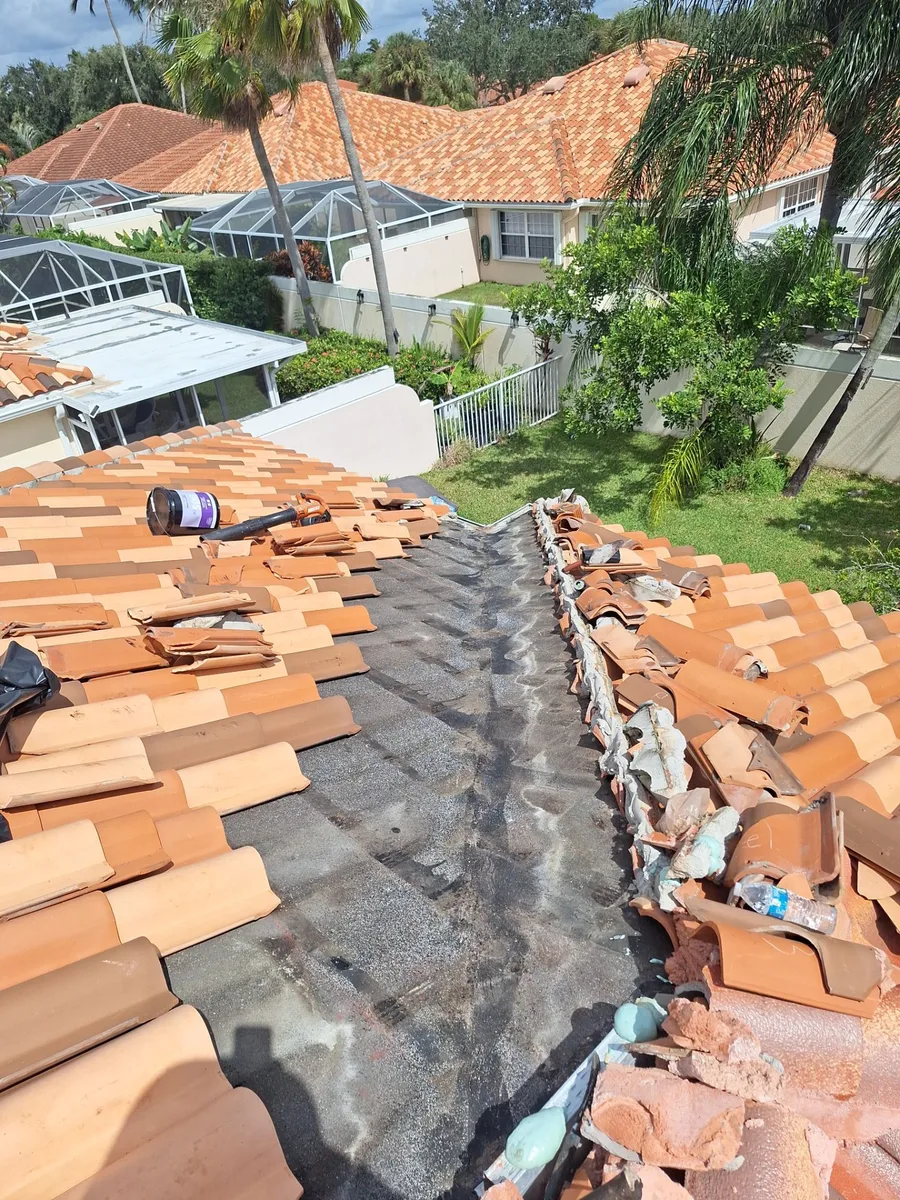 Clay tile valley opened for repair in West Palm Beach with tiles stacked aside and aged underlayment exposed