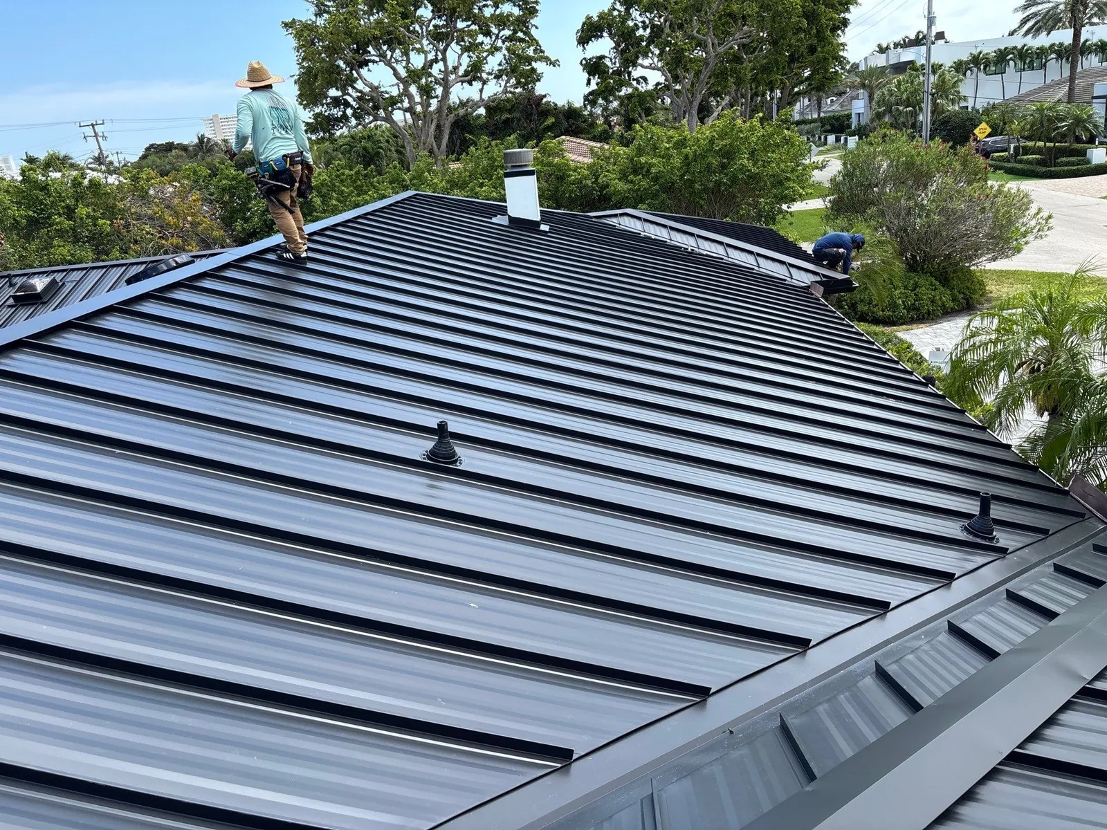 All Phase Construction USA crew finishing a standing-seam metal roof in Boca Raton