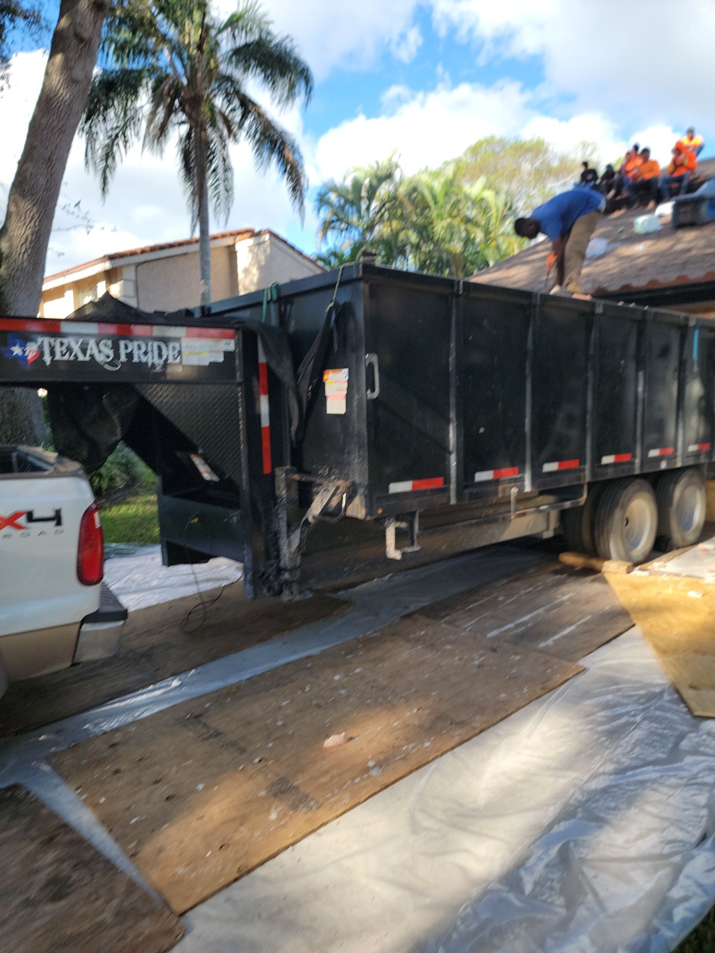 Roofing catch-all debris containment system protecting landscaping and property during South Florida roof replacement